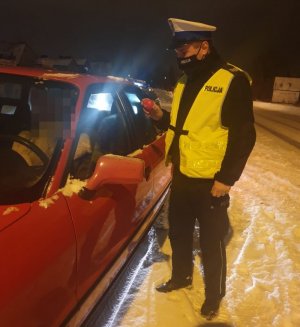 policjant dający czerwone serduszko osobie siedzącej w samochodzie