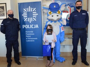 dziewczynka z policjantami i maskotą komendy