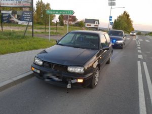 uszkodzony volkswagen golf, z tyłu radiowóz nieoznakowany, w oddali jadący samochód osobowy