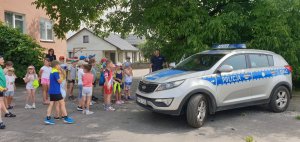 dzieci i policjanci obok oznakowany radiowóz