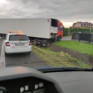 samochód ciężarowy ugrzązł na poboczu, obok samochód osobowy