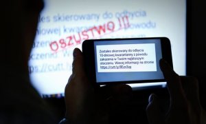 ekran monitora z napisem oszustwo oraz telefon trzymany w dłoniach z treścią wiadomości sms