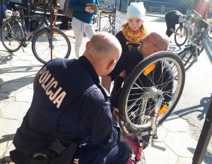 policjant znakujący rower, obok dziewczynka ze swoim ojcem