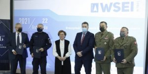 Uczestnicy spotkania podczas wspólnego zdjęcia dr hab. Mirosław Jarosz - Rektor WSEI,  mgr Teresa Bogacka Kanclerz WSEI, dr. Mariusz Paździor Prorektor ds. Kształcenia i Spraw Studenckich a także przedstawiciele służb mundurowych: płk. Tadeusz Nastarowicz Dowódca 2 Lubelskiej Brygady Obrony Terytorialnej, płk Andrzej Drozd Komendant Oddziału Żandarmerii Wojskowej w Lublinie oraz nadinspektor Artur Bielecki - Komendant Wojewódzki Policji w Lublinie