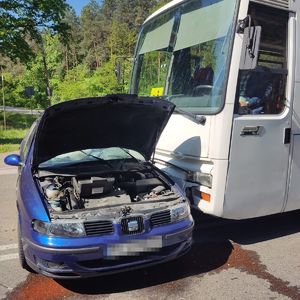 dwa pojazdy uczestniczące w zdarzeniu drogowym, otwarta maska samochodu osobowego i autobus