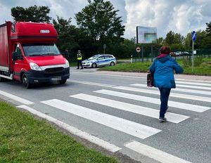 piesza na przejściu dla pieszych, w oddali radiowóz