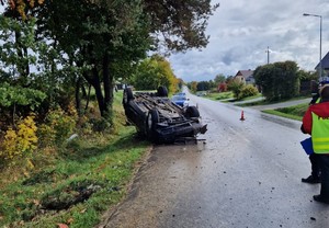 samochód po dachowaniu obok policjanci wykonujący czynności służbowe