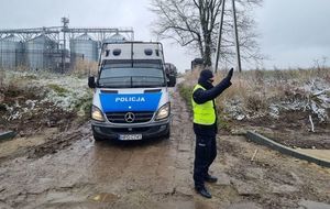 policjant z uniesioną ręką, w tle radiowóz