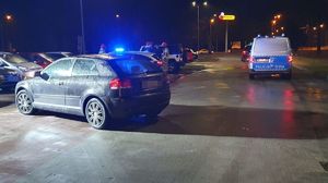 Na parkingu na którym doszło do potrącenia chłopca stoi audi, obok radiowóz, w oddali kilka samochodów