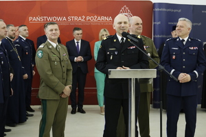 Zdjęcie przedstawia spotkanie przedświąteczne służb mundurowych. W pierwszym planie zdjęcia widzimy przemawiającego do zgromadzonych gości Komendanta Państwowej Straży Pożarnej w Lublinie nadbrygadiera Grzegorza Alinowskiego