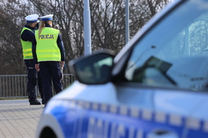 policjanci obok radiowozu dokonują pomiaru prędkości