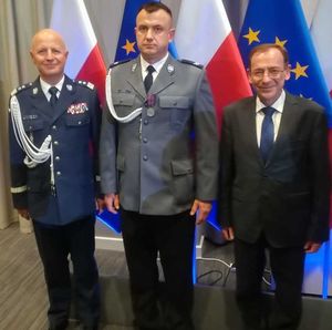 odznaczony policjant stoi z komendantem głównym policji oraz ministrem