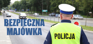 napis bezpieczna majówka i policjant