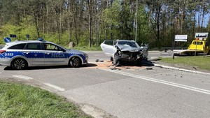 uszkodzony pod zderzeniu samochód marki Hyundai oraz radiowóz w tle i laweta