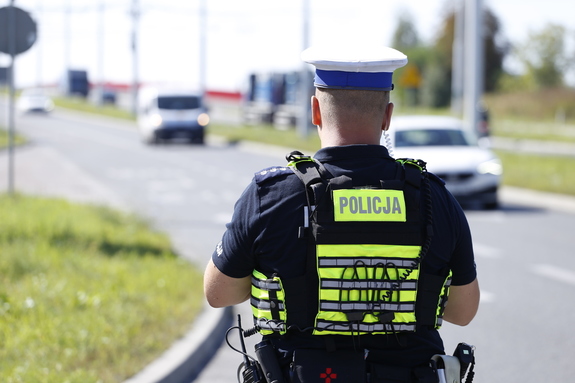 policjant ruchu drogowego w tle droga i jadące po niej samochody