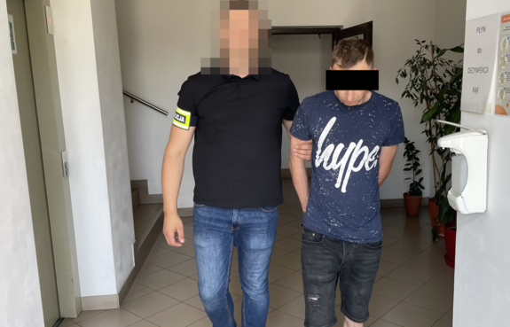 policjant prowadzi zatrzymanego