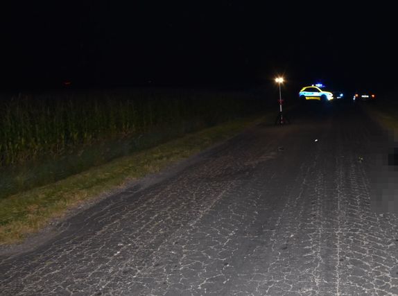 droga na której doszło do wypadku, w tle radiowóz z włączonymi sygnałami świetlnymi