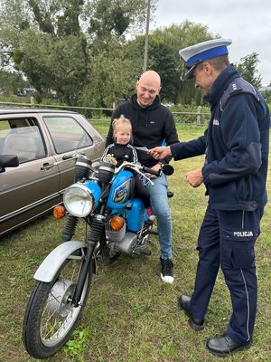 policjant wręcza ulotkę mężczyźnie który siedzi na motocyklu