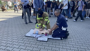 funkcjonariusz straży pożarnej oraz policjant podczas pokazu udzielania pierwszej pomocy na fantomie