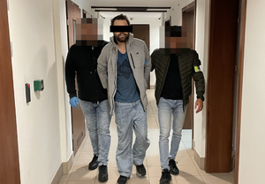 policjanci prowadzą zatrzymanego