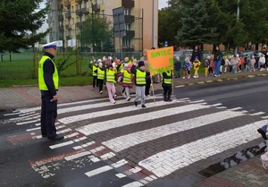 dzieci z transparentami &quot;świeć przykładem&quot; przechodzą przez przejście dla pieszych