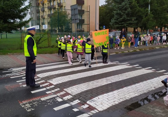 dzieci z transparentami &quot;świeć przykładem&quot; przechodzą przez przejście dla pieszych