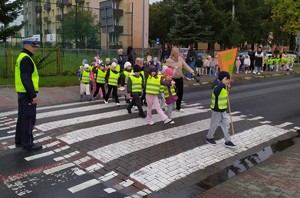 dzieci z transparentami &quot;świeć przykładem&quot; przechodzą przez przejście dla pieszych