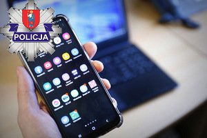 telefon trzymany w ręce w tle laptop