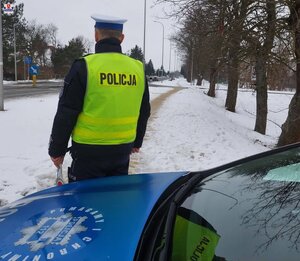 policjant stojący obok radiowozu