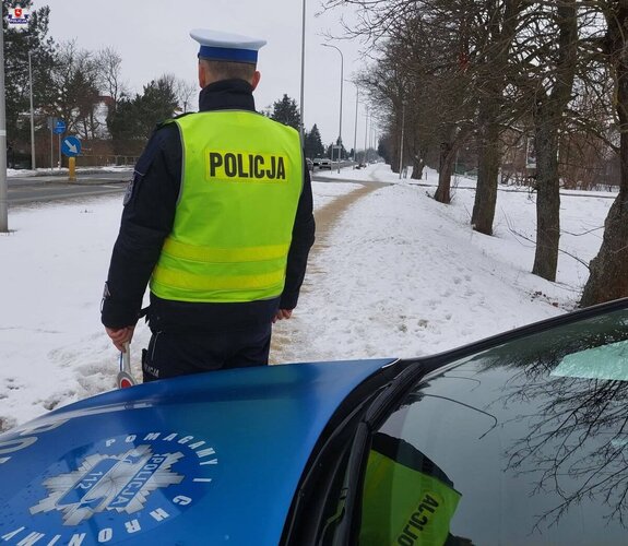 policjant stojący obok radiowozu