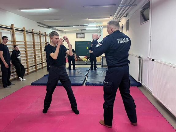 policjant z uczniem ćwiczą chwyty obezwładniające
