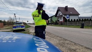 policjantka mierzy prędkość obok radiowozu oznakowanego