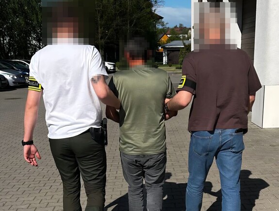 policjanci prowadzą osobę zatrzymaną