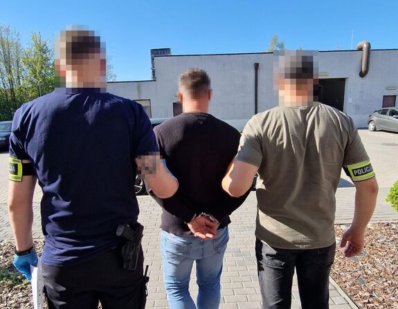 policjanci prowadzą zatrzymanego mężczyznę