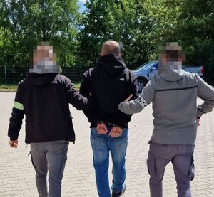dwóch policjantów prowadzących zatrzymanego