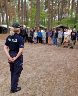 policjantka opowiada o zasadach bezpieczeństwa, w oddali harcerze