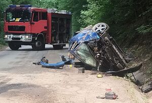przewrócone na bok audi po uderzeniu w skarpę, w oddali wóz strażacki