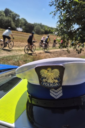 czapka policyjna a w tle rowerzyści