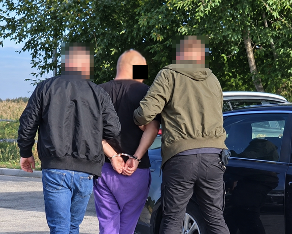 policjanci kryminalni prowadzą zatrzymanego