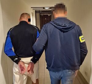 policjant prowadzi osobę zatzrymanego
