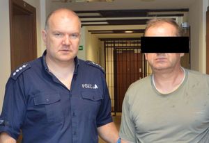 policjant prowadzi zatrzymanego 55 -latka